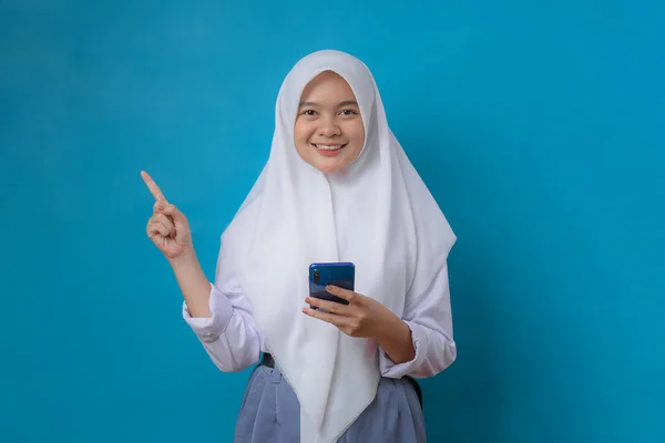 Portret Młodej Zrelaksowanej Uczennicy Hidżabem Trzymającej Telefon Komórkowy Niebieskim Tle — Zdjęcie stockowe