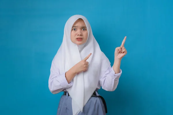 Młoda Studentka Hidżabem Nieszczęśliwa Wskazująca Bok Nad Odizolowanym Niebieskim Tle — Zdjęcie stockowe