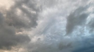 Gün batımında gökyüzünde fırtına bulutlarının dinamik hareketi, bulutlar arasında zarif bir şekilde uçan hızlı kuşlar. Karanlık bulutların etkileşimi ve renkli günbatımı doğanın güzelliğini ve gücünü gösteren büyüleyici bir sahne yaratır..