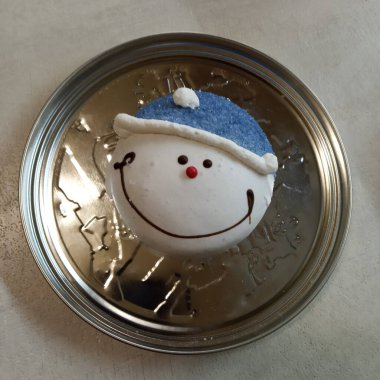 a smiling snowman gingerbread cookie resting on a metallic surface, creating a delightful contrast between the warmth of the festive treat and the coolness of the metal. Festive Delight clipart