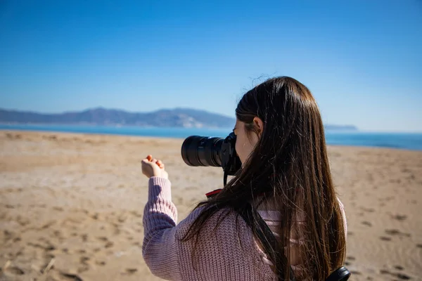 美しい女性写真を撮る海のシェル保持それとともに彼女の手閉じるバックショットでザビーチ — ストック写真