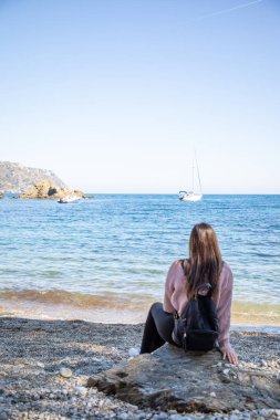 Güzel kadınlar çakıl taşlı bir plajda oturup fotokopi çekiyorlar.