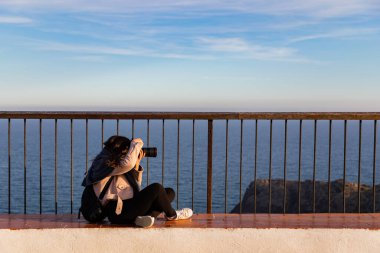 Güzel kadınlar gün batımında fotokopi çekerek oturup resim çekiyorlar.