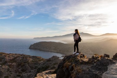 Gün batımında bir uçurumun kenarında duran güzel kadınlar ve arka planda fotokopi alanı olan deniz.