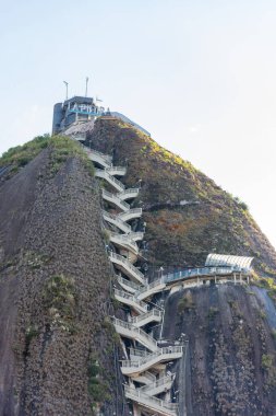 Güney Amerika 'da popüler bir turizm merkezi olan Guatape, Antioquia, Kolombiya' daki zirveye çıkan merdiveni ile El Penol Kayası.