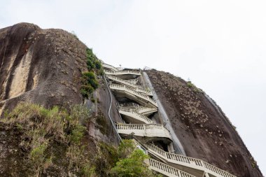 Güney Amerika 'da popüler bir turizm merkezi olan Guatape, Antioquia, Kolombiya' daki zirveye çıkan merdiveni ile El Penol Kayası.