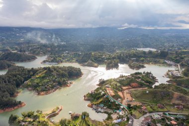 Antioquia, Kolombiya 'daki Guatape rezervuarını gösteren panoramik bir manzara, birbirine bağlı adaları, su kanallarını ve yakındaki kentsel ve kırsal manzaraları vurguluyor..