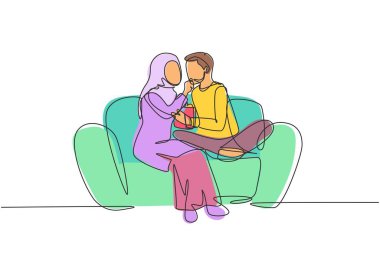 Single continuous line drawing romantic Arabian couple sitting relaxed together on sofa, woman feeding popcorn to man. Celebrate wedding anniversary. One line draw graphic design vector illustration