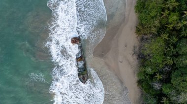 Manzanillo, Limon, Kosta Rika 'da turkuvaz suyu ve yemyeşil ağaçlarla dolu kumlu bir sahildeki gemi enkazlarının hava manzarası. Yüksek kalite fotoğraf