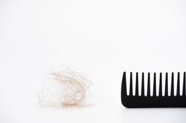 Beyaz arka planda saçı dökülmüş siyah plastik tarak.