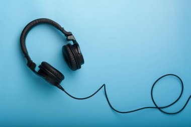 Mavi arka planda siyah kulaklıklar.