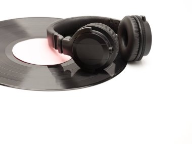 Beyaz arka planda siyah kablosuz kulaklık ve vinil plak.