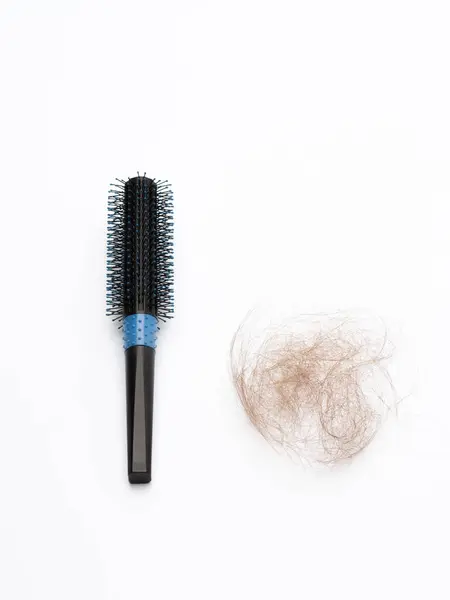 Siyah plastik saç fırçası, beyaz arka planda saçı dökülmüş.