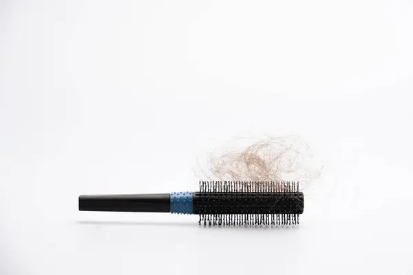 Siyah plastik saç fırçası, beyaz arka planda saçı dökülmüş.