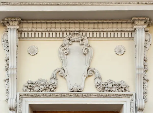 Eski bir binanın ön cephesinde güzel bir sıva süslemesi ve boş bir aile amblemi.