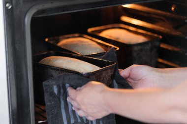 Ev yapımı ekmek pişirmenin başlangıcı. Fırıncı bir hamur ile kalıpları fırına sokuyor.