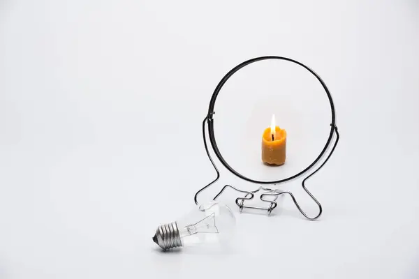 Ampul aynaya bir mum olarak yansıtılır. Teknolojilerin sembolik karşılaştırması