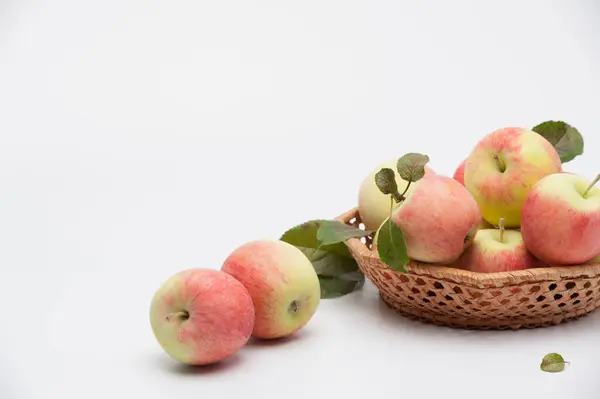 Beyaz arka plandaki hasır plakada sulu olgun elmalar