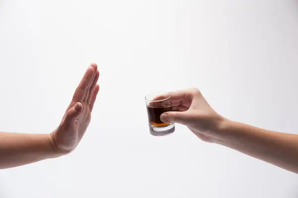 Bir el içki ikram eden bir bardak alkolü tutarken, diğer el de dur işareti yapıyor.