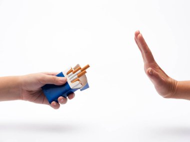 Bir insan eli bir paket sigara tutuyor sigara içme teklifi yapıyor ve diğer el de jesti durduruyor.