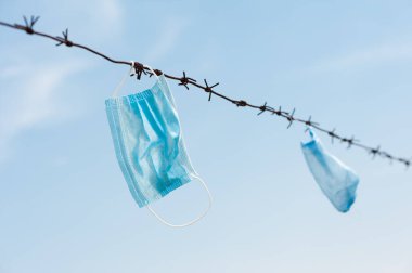 Dikenli tellerde asılı tıbbi maskeler.