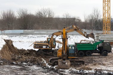 Lviv, Ukrayna - 01.12.2022: Ağır makineler kullanarak bir çukur kazma, yükleme ve inşaat alanından toprak çıkarma süreci. İnşaatın ilk aşamasında toprak çalışmaları