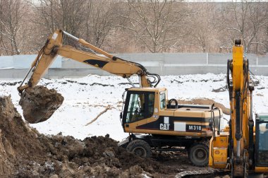 Lviv, Ukrayna - 01.12.2022: Ağır makineler kullanarak bir çukur kazma, yükleme ve inşaat alanından toprak çıkarma süreci. İnşaatın ilk aşamasında toprak çalışmaları