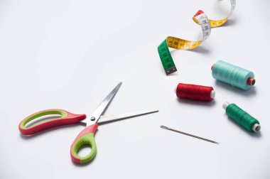 Terzinin envanteri. Beyaz arkaplanda renkli iplikler, makas, iğne ve elastik cetvel seti