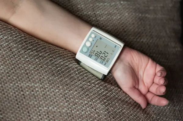 Dijital basınç göstergesi ve insan elinin üzerindeki bazı göstergeler. Genç bir kadının evdeki kan basıncını ölçme süreci