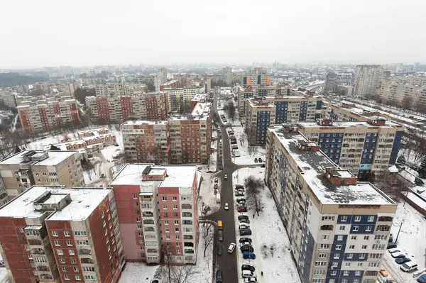 Sisli şehrin eski bölümündeki evlerin karla kaplı çatılarında yeni bir binanın penceresinden manzara
