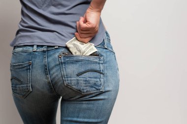 Kadın pantolonunun arka cebinden 100 dolarlık banknot çıkartıyor.