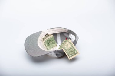 İçinde birkaç dolar olan bir şapka beyaz bir arka planda yatıyor.