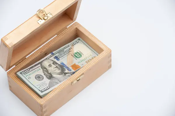 Beyaz arka planda içi para dolu küçük tahta bir kutu..