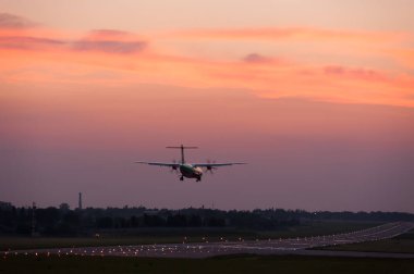 Günbatımı arka planına inen uçak.