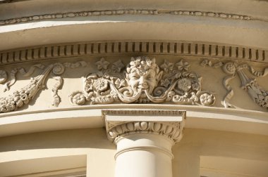 Eski bir binanın ön cephesinde güzel bir sıva süslemesi ve efsanevi adamın bas-yardım kafası.