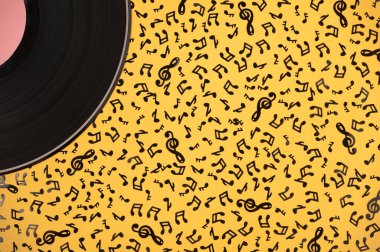 Müzikal kompozisyon. Sarı arka planda plak ve siyah müzik notaları