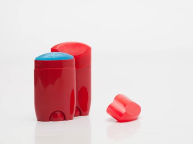 Beyaz arka planda erkekler için kuru deodorant içeren kırmızı kaplar.