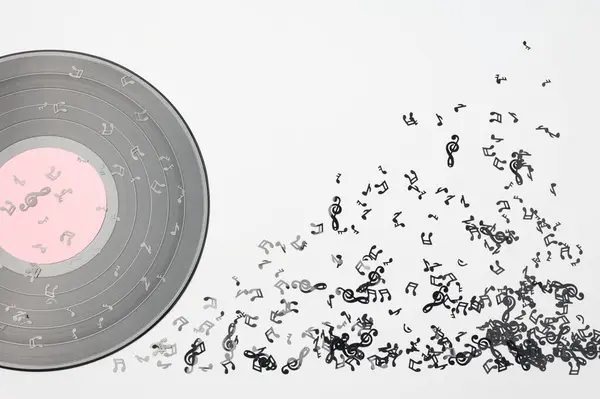 Vinil müzik diski beyaz arka planda notaları olan bir plakaya benziyor.