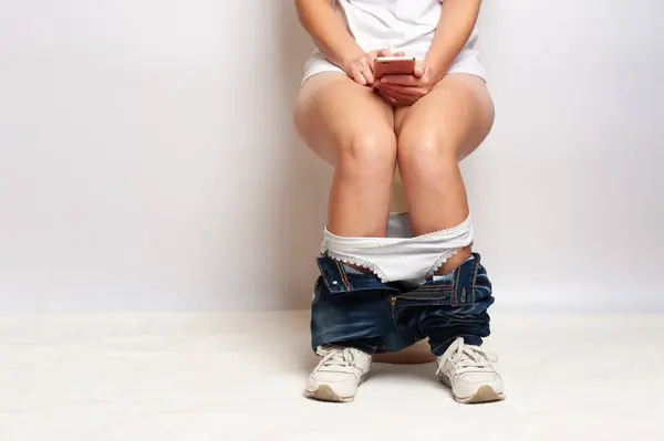 Kadın bacakları tuvalette otururken külotlu.