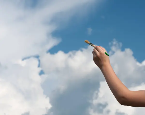 Fırçayla sol el gökyüzünü ve bulutları boyar..