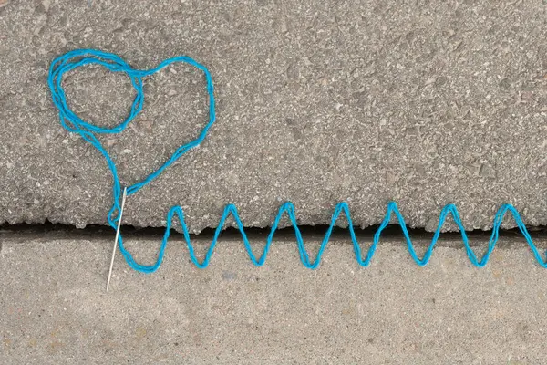 Asfalttaki çatlak, uyumsuz ve mantıksız şeylerin birleşmesini sembolize eden renkli ipliklerle dikilmiş.