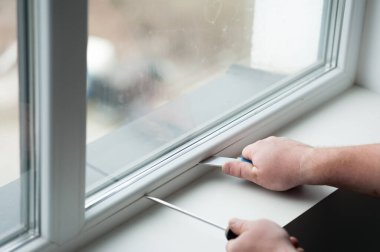 Mühürleme köpük bandı üstünde pencere içinde ev koyarak inşaat işçisi