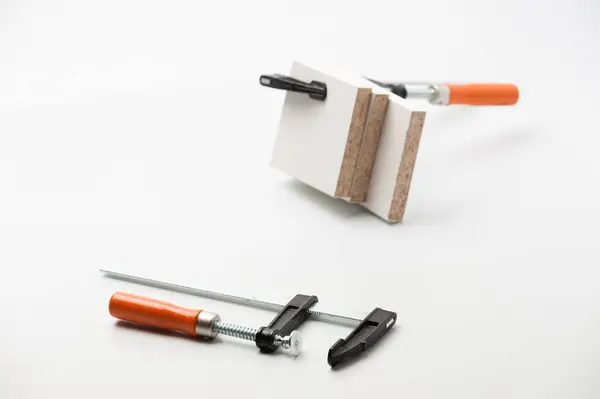 Beyaz arka planda bir çift marangoz kıskacı kullanılıyor