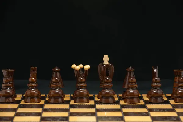 Satranç tahtası ve karanlık arkaplanda düzenlenmiş taşlar.