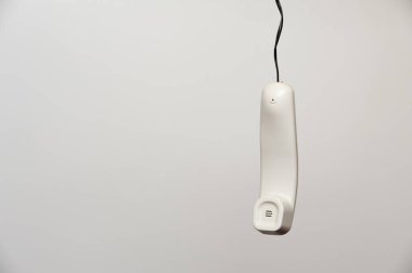 Modası geçmiş bir ev telefonunun asılı beyaz bir telefonu.