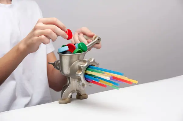 Genç bir adamın elleri plastik atıkları öğütücüye attı. Bu plastik atıkları ikincil bir ürüne dönüştürmenin sembolik bir görüntüsü..
