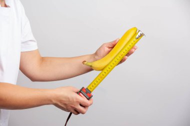 Dişi eller bir mezura kullanarak olgun bir muzun boyutunu ölçüyorlar.