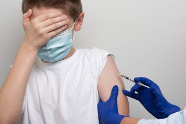 Tıbbi ve aşı konusu. Şırıngalı hemşirenin elleri korkmuş beyaz çocuğa aşı yapıyor.