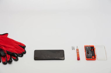 Beyaz arkaplanda tamir için bozuk ekranı, tornavidaları ve bitleri olan akıllı telefon.