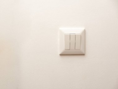 Duvara üç düğmeli bir elektrik düğmesi takılmış.
